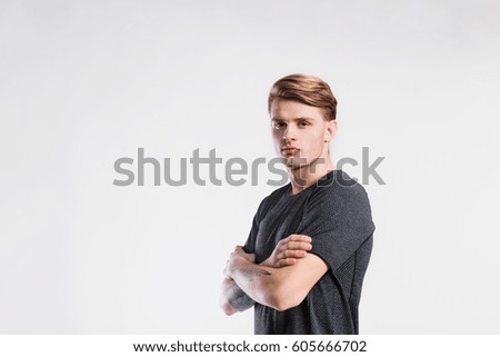 Handsome man in gray t-shirt, tattoo on forearms, studio shot.