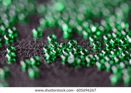 Transparent green seed beads on a dark leather background