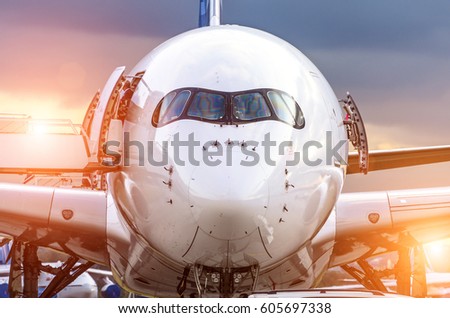 Airplane view from the front cockpit fuselage at sunset at the airport. Royalty-Free Stock Photo #605697338