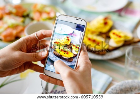 Smartphone taking picture from organic healthy sandwiches. Woman hand. Close-up of table with different food.