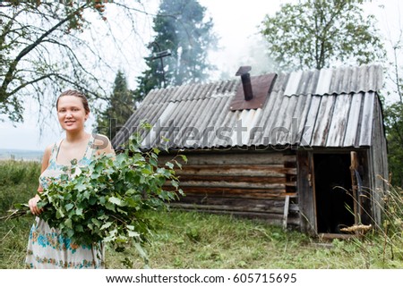 Young woman with with fresh birch broom and heating bath on background