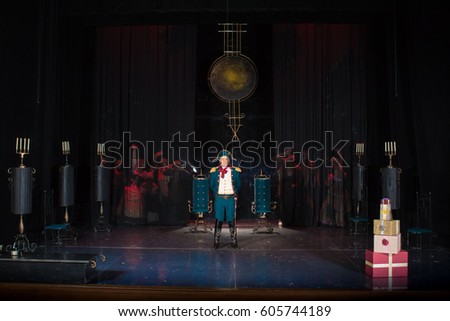 Actors, men in old clothes frock coats and uniforms and women in medieval dresses with lush skirts posing on stage in the background of scenery
