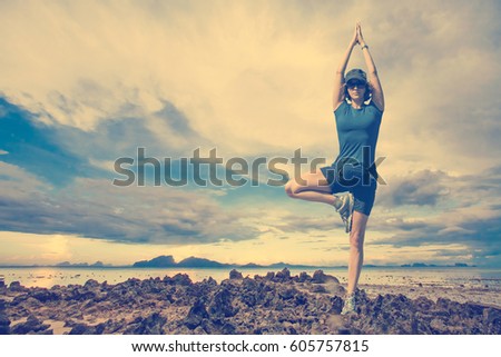 The woman is engaged in yoga on a background of rocks, the sea and sky. Toned