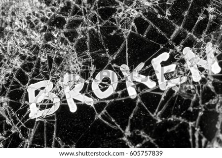 White inscription BROKEN on the black  cracked touch screen phone, background, texture