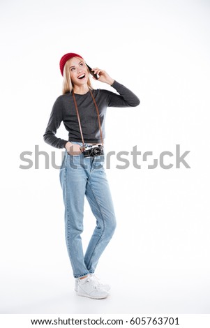 Full length of a happy smiling young woman photographer talking on mobile phone isolated over white background