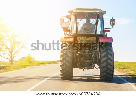 Tractor rides on the asphalt road in the sunlight Royalty-Free Stock Photo #605764286