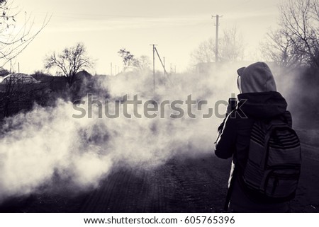 Village in smoke. Photographer takes picture of smoky road in evening sun. Rural landscape in spring. Toned black and white photo