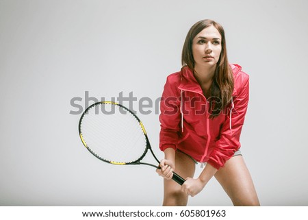 Beautiful young woman playing tennis in studio 