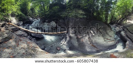 The mountain river is enclosed in stones. Panoramic picture with a large angle.