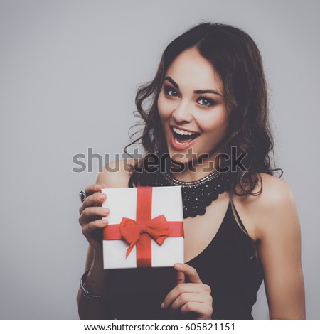 Young woman happy smile hold gift box in hands, isolated over gray background