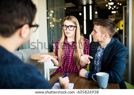 Beautiful couple is talking with manager or realtor, who is making notes at office