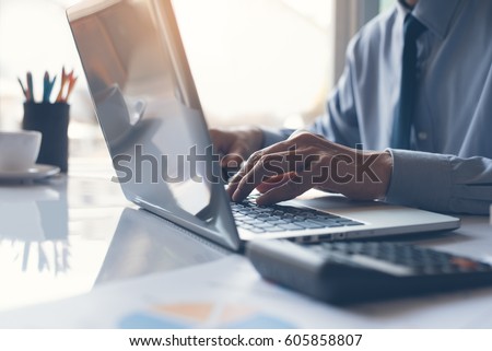 Business man or accountant working on laptop computer with business document, graph diagram and calculator on office table Royalty-Free Stock Photo #605858807