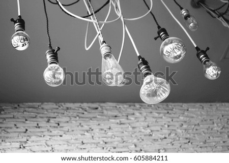 Grey scale picture of Light bulbs decoration from the ceiling of the white-gray room