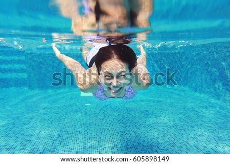 Young asian woman having fun underwater in swimming pool.