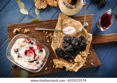 Bowl with delicious yogurt and ingredients on wooden board