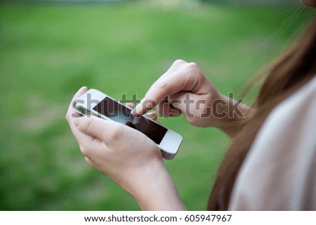 Close up of woman using mobile smart phone in the park.