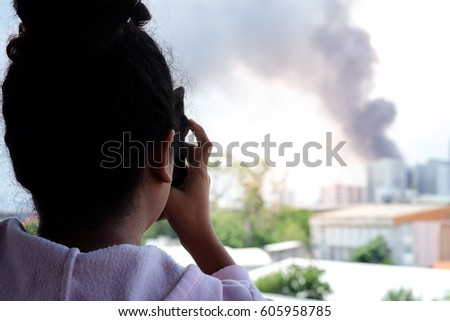 Asian women are using a smart phone to photograph a new fire incident.