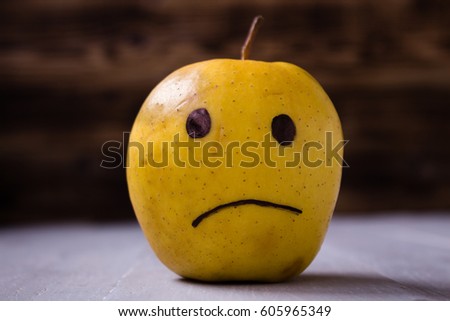 yellow apples with drawn emotions on wooden background