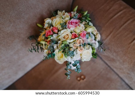 Wedding bouquet of roses lying with rings on the chair close-up. The bride's bouquet. 