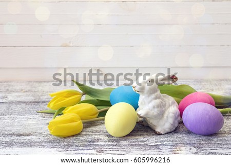 Easter decoration with rabbit, easter eggs and yellow tulips. Space for text.
