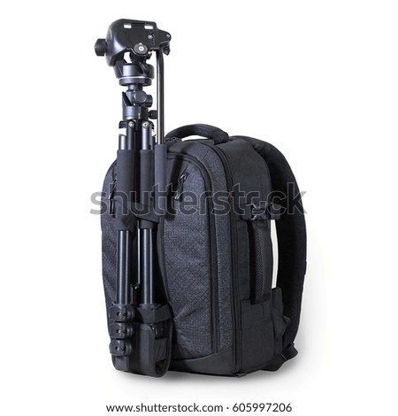 Half-turn view of a black camera backpack with a metal tripod buckled up to it isolated on white background