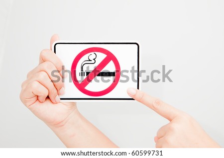 A women holding and pointing at a "no smoking" sign.