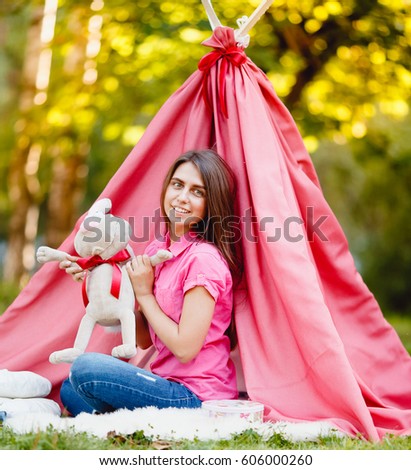 Girl with a toy hare against a background of a pink tent and sunset, spring, summer. The sun.