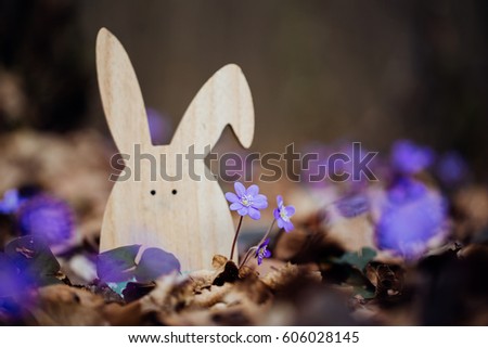 Easter rabbit in the forest with flowers and eggs. Spring time. 