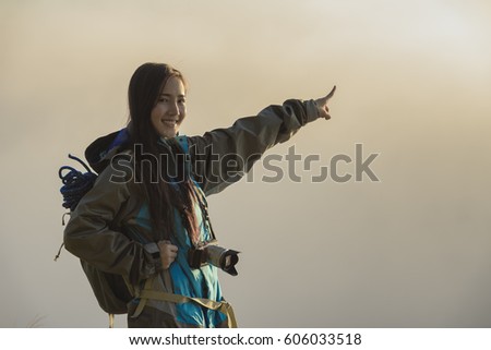 The adventurer stands at the top of the mountain with foggy morning sky with the shadow of a distant mountain,freedom lifestyle concept traveller with backpacks relaxing.