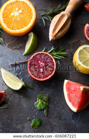 The pattern of slices of orange, lemon and grapefruit on a dark concrete background with rosemary, flat lay