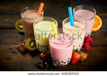 Selection of bubble tea in a tea house with assorted fruit flavors, caramel and chocolate with fresh ingredients on a wooden table viewed high angle