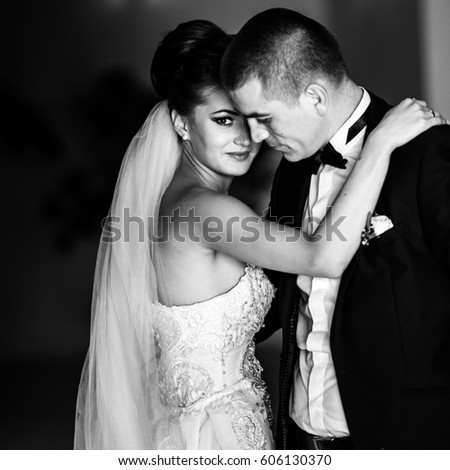 Black and white picture of awesome bride holding her hands on groom's shoulders