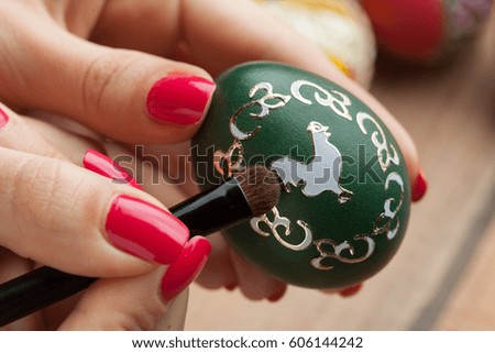 Easter eggs and natural wooden country table with woman hand coloring eggs