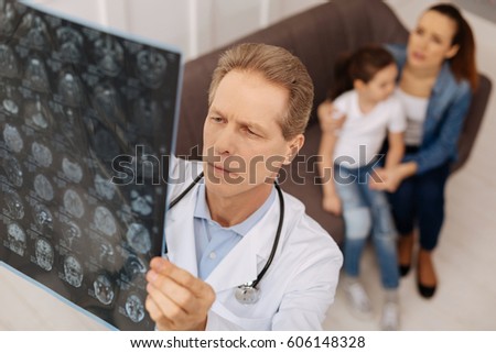 Concerned experienced doctor looking through brain scans