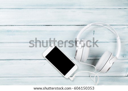 Smartphone and headphones over rustic wooden table. Top view with copy space