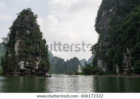 Cruising on small rowboats which rowers paddle at Trang An in Ninh Binh, Vietnam. Tourists are looking at the scenery which is a UNESCO World Heritage Site.