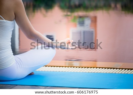 Young people training yoga and meditation at poolside