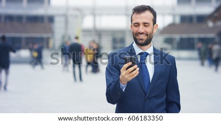 A businessman answering the phone, send messages and smiles for the beautiful job news and in the background you see a people. Concept: technology, telephony, business trips, business, wall street Royalty-Free Stock Photo #606183350