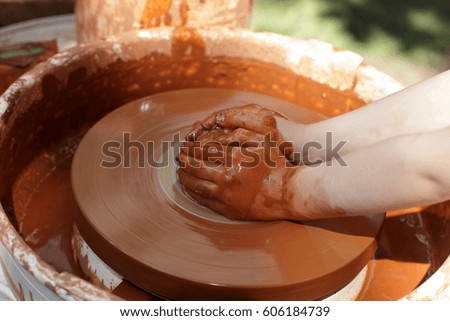 Hands of a potter on the pottery wheel outdoor