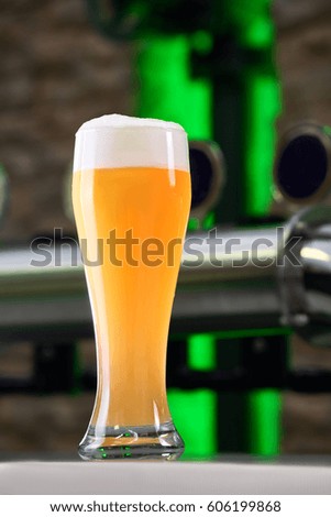 Glass of light beer on a dark pub. Glasses of Beer on a bar table. Beer Tap on background