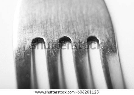 Single fork with texture detail of everyday wear and tear on the tines.  Shot on a white background. Shallow depth of field.