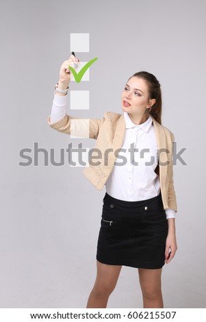 Young business woman checking on checklist box. Gray background.