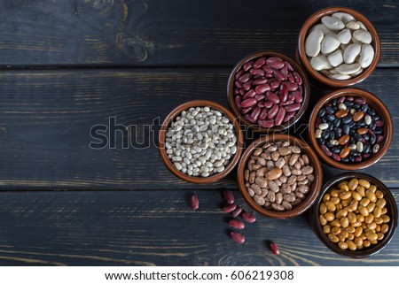 Assortment of beans on black wooden background. Soybean, red kidney bean, black bean,white bean, red bean and brown pinto beans Royalty-Free Stock Photo #606219308