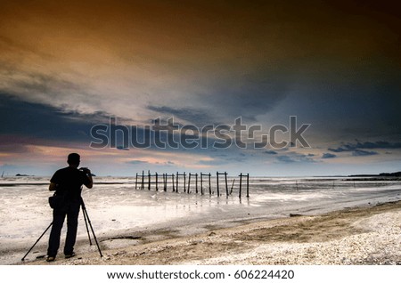 unidentified man taking photo during sunset moment near the beach.magical sky color and low tide water
