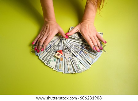 Woman hands with little house and dollars on background. top view. copy space
