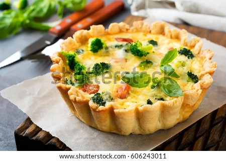 Homemade quiche tart with red fish salmon, broccoli, basil, seasonings and cheese on a gray stone background. Selective focus.
 Royalty-Free Stock Photo #606243011