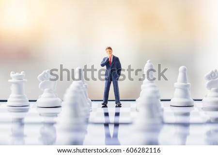 Business decision making concept. Miniature people : small businessman figure standing and walking on chessboard with chess pieces Royalty-Free Stock Photo #606282116