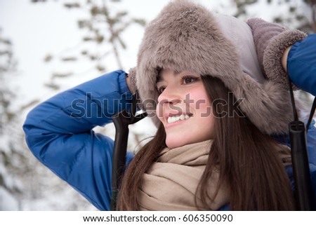 Beautiful girl skiing in a pine forest in a blue jacket