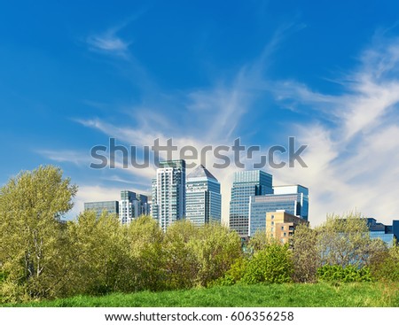 London, UK, Canary Wharf skyline in springtime, half-hidden behing trees under gorgeous feather clouds