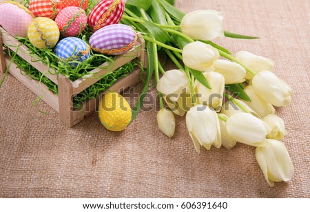 Colorful Easter eggs and white tulips on a burlap